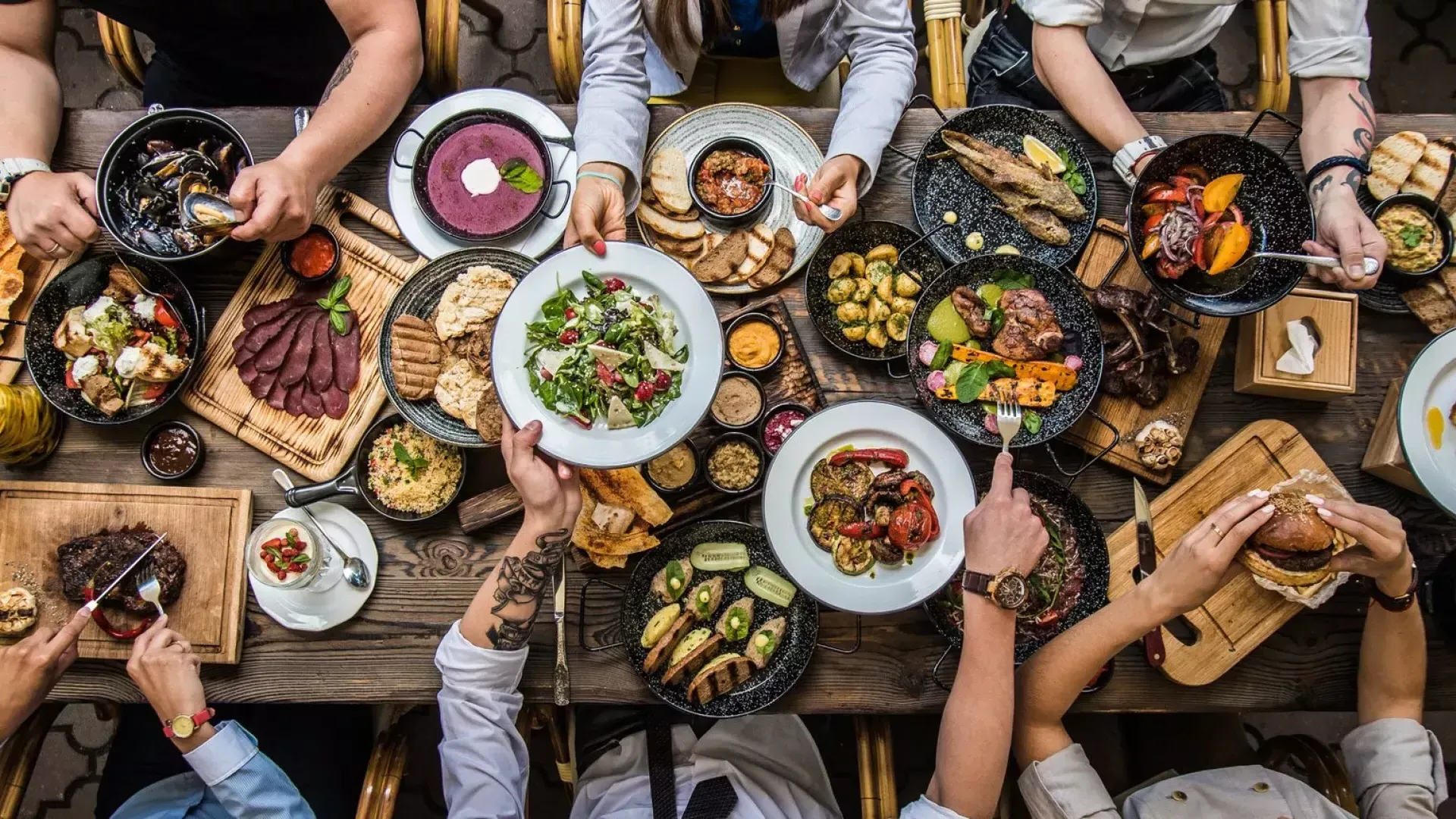 People sitting at a dining table, sharing food.